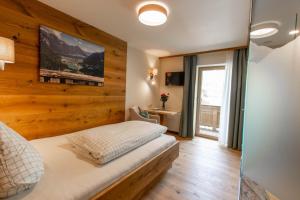 a bedroom with a wooden accent wall and a bed at Pension&Appartements Marxenhof in Pertisau