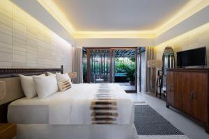 a bedroom with a large white bed and a television at The Kemilau Hotel & Villa Canggu Bali in Canggu
