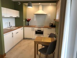 a kitchen with white cabinets and a table with chairs at Aqua Apartments in Reda