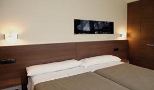 a bedroom with two beds and a tv on the wall at Hotel Izelai in Alsasua