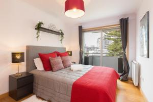 a bedroom with a bed with red pillows and a window at Deluxe Modern Flat with Balcony by Host Wise in Porto