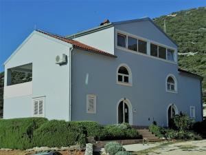 a white house with a hill in the background at Sunny Blue Apartament in Nerezine