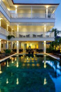 a large swimming pool in a hotel with a large building at Samsara Inn in Legian