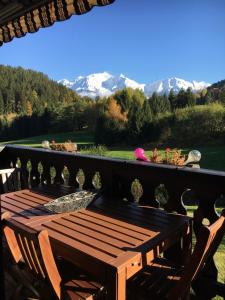 a wooden table and chairs on a balcony with mountains at Sallanches 3101 Route de Nant Cruy immeuble le Grand R in Sallanches