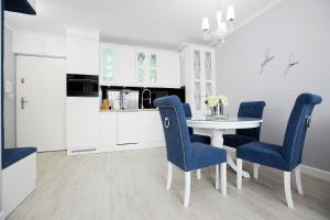 コウォブジェクにあるApartamenty NAVIGATOR-Bliżej Morza 94の白いキッチン(青い椅子、テーブル付)