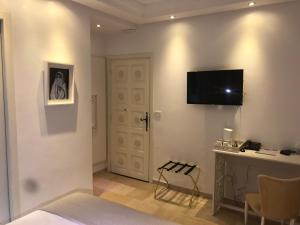 a bedroom with a bed and a desk and a television on a wall at Dar Corniche La Marsa (Adults Only) in La Marsa