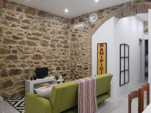 a living room with a stone wall and a green couch at Casa Antico Forno in Manciano