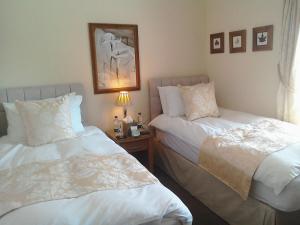 South Lodge Guest House في بريدلينغتون: غرفة نوم بسريرين وطاولة بها مصباح