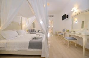 a white bedroom with a white bed and a desk at Kamari Hotel in Platis Yialos Mykonos
