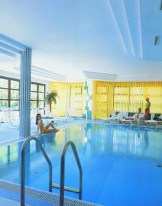 a large swimming pool with people sitting around it at Hotel Bergland Obsteig in Obsteig