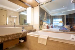Graceland Bangkok by Grace Hotel - SHA Extra Plus في بانكوك: حمام مع حوض كبير ومرآة كبيرة