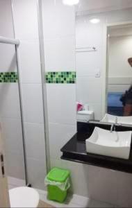 W łazience znajduje się umywalka, toaleta i lustro. w obiekcie Apto na Praia de Guaibim w mieście Guaibim