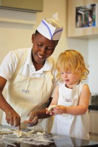 a woman and a little girl in a kitchen preparing food at The Residence Zanzibar in Kizimkazi