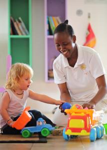 a woman helping a child play with a toy car at The Residence Zanzibar in Kizimkazi