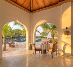 a dining room with a table and a view of the ocean at The Residence Zanzibar in Kizimkazi