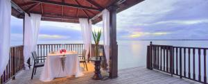 a table with a candle on a porch next to the water at The Residence Zanzibar in Kizimkazi