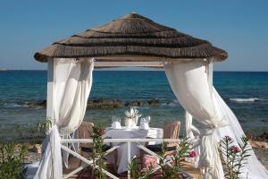 a dinner table under a gazebo on the beach at Aquagrand Exclusive Deluxe Resort Lindos - Adults only in Lindos