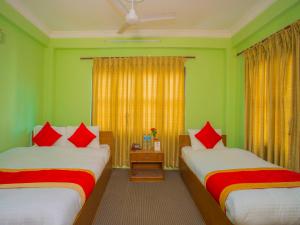 two beds in a room with green walls and red pillows at Waling Fulbari Guest House in Bālāju