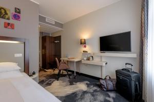 a hotel room with a bed and a desk with a television at Mercure München am Olympiapark in Munich