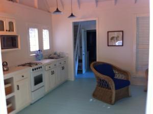 a kitchen with white cabinets and a blue chair at Spice Cottage in Five Islands Village