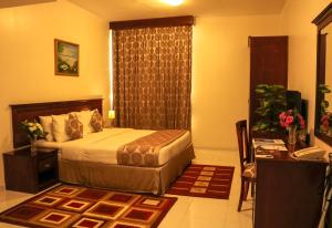 a bedroom with a bed, a dresser and a lamp at Al Maha Regency Hotel Suites in Sharjah