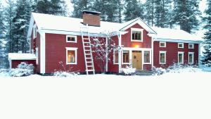 a red house with a ladder in the snow at Rehto in Rovaniemi