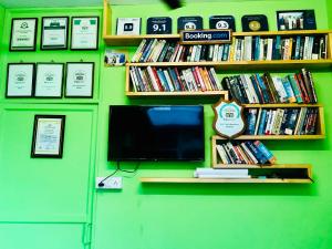 a tv on a green wall with books at Bastian Homestay in Cochin