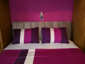 a bed with purple and white sheets and pillows at Guest house Irena in Omiš