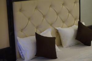 a bed with white pillows and a large headboard at Hotel Khalsa -Lake View in Pachmarhī