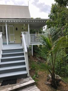 ein weißes Haus mit einer Veranda und einer Treppe in der Unterkunft Spice Cottage in Five Islands Village