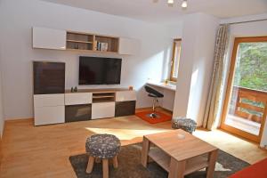 a living room with a television and a table and chairs at Apartments Weißstein in Gries im Sellrain