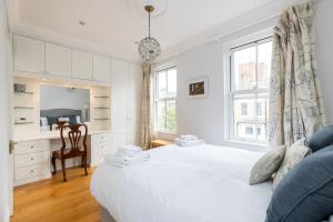 a white bedroom with a bed and a desk at ALTIDO Stunning 3 bed, 2 bath house with garden and rooftop terrace in London