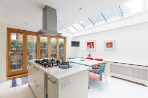 a kitchen with a stove top oven next to a table at ALTIDO Stunning 3 bed, 2 bath house with garden and rooftop terrace in London