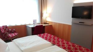 a hotel room with a bed and a television at Stadtoase Kolping Hotel in Linz