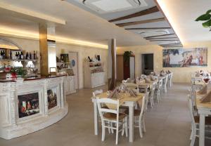 un restaurant avec des tables et des chaises blanches et un bar dans l'établissement Agriturismo Corte Foscara, à Malcontenta