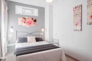 biała sypialnia z łóżkiem i różowym kwiatem na ścianie w obiekcie 16 Benal Acogedor y en 1ª linea w mieście Benalmádena