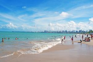 a group of people playing in the water at a beach at Ótimo apto Praia Bessa in João Pessoa