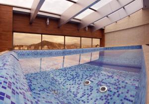 a large swimming pool in a building with blue tiles at Apart Hotel Selenza in Cochabamba