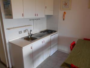 a white kitchen with a sink and a stove at Le Case Punta Negra in Stintino