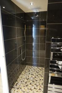 a bathroom with a shower with black walls and tile floors at Halvard Hotel in Douglas