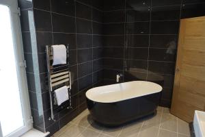 a bath tub in a bathroom with black tiles at Halvard Hotel in Douglas