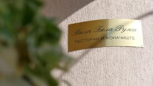 a sign on the side of a wall with a plant at B&B Vila Bela Ruza in Sremska Mitrovica
