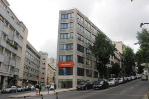 a tall building on a city street with parked cars at easyHotel Lisbon in Lisbon