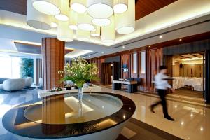 a person walking through a hotel lobby with a table at Classic Kameo Hotel & Serviced Apartments, Ayutthaya in Phra Nakhon Si Ayutthaya