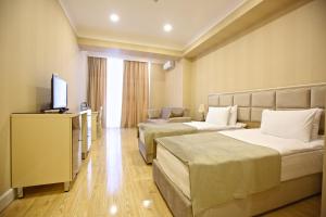 a hotel room with two beds and a flat screen tv at Rusel Hotel in Baku