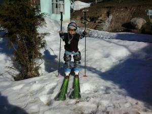 ein kleines Kind steht auf Skiern im Schnee in der Unterkunft Friendship (guest house)* in Arslanbob