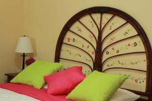 a bedroom with a bed with green and red pillows at Hotel Colibri in Managua