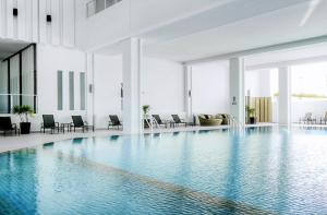 a large swimming pool in a building with chairs at Classic Kameo Hotel & Serviced Apartment, Rayong in Rayong