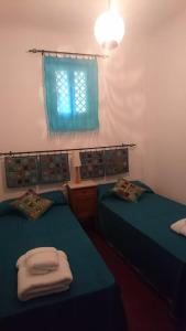 グラナダにあるLa Casita de Granadaのベッド2台、青いカーテン付きの窓が備わる客室です。