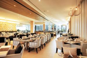 Classic Kameo Hotel & Serviced Apartment, Rayong في رايونغ: غرفة طعام مع طاولات وكراسي في مطعم